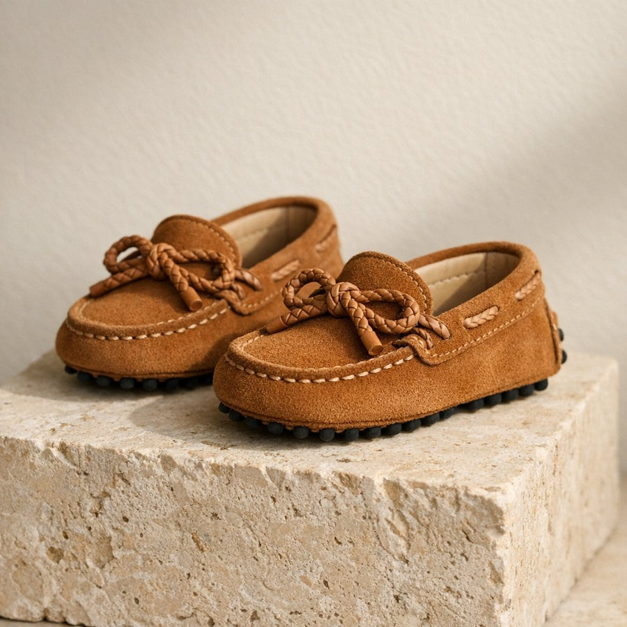 Mocassins enfant en daim camel à nœud, posés sur un bloc de pierre