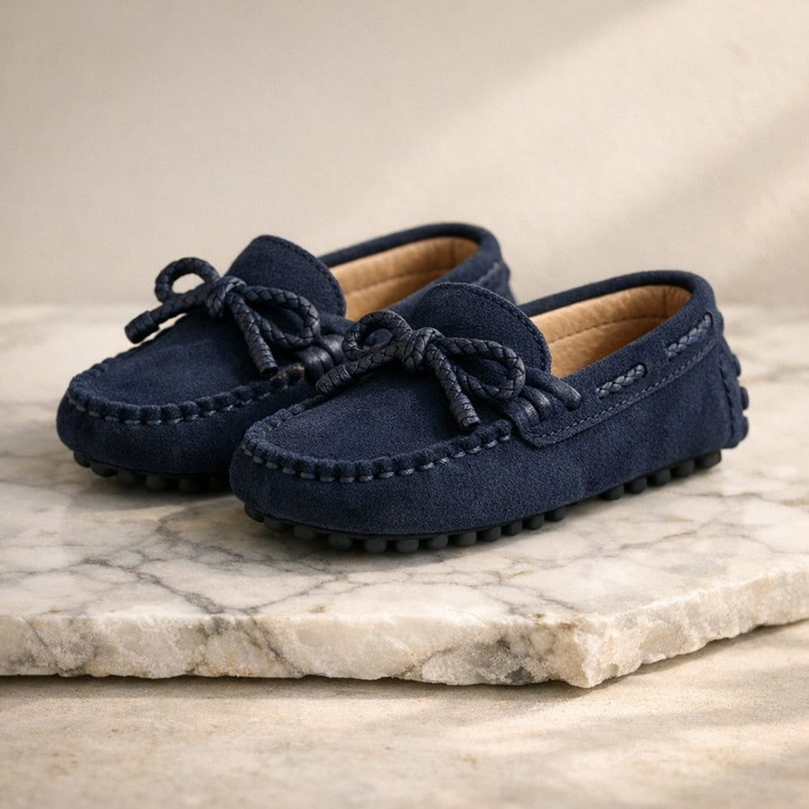 Mocassins garçon en daim bleu marine à nœud, posés sur du marbre