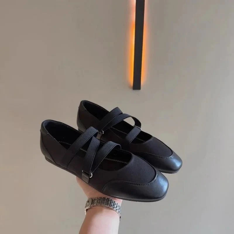 paire noire tenue à la main devant un mur beige
