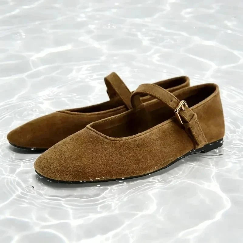 Ballerine marron foncé vue de face, bride et boucle visibles, sur un fond d'eau