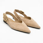 Vue de trois quarts d’une paire de ballerines beige avec boucle dorée