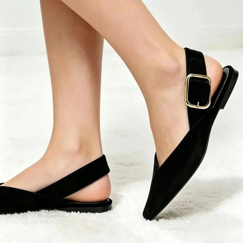 Pieds portant une paire de ballerines noires à bride arrière sur sol clair