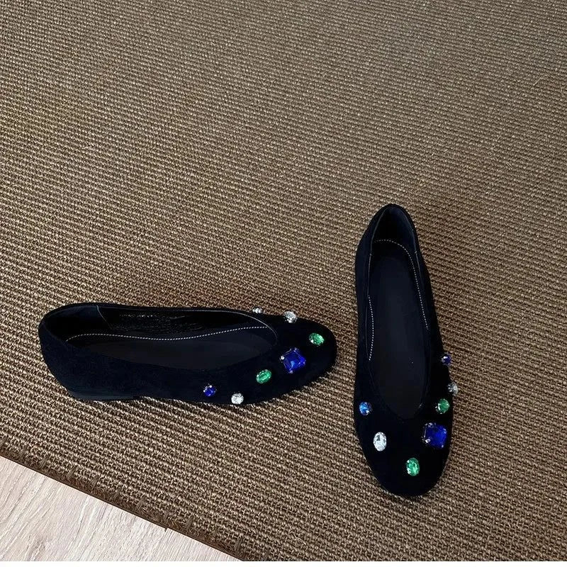 deux ballerines noires posées sur un tapis avec pierres décoratives bien visibles