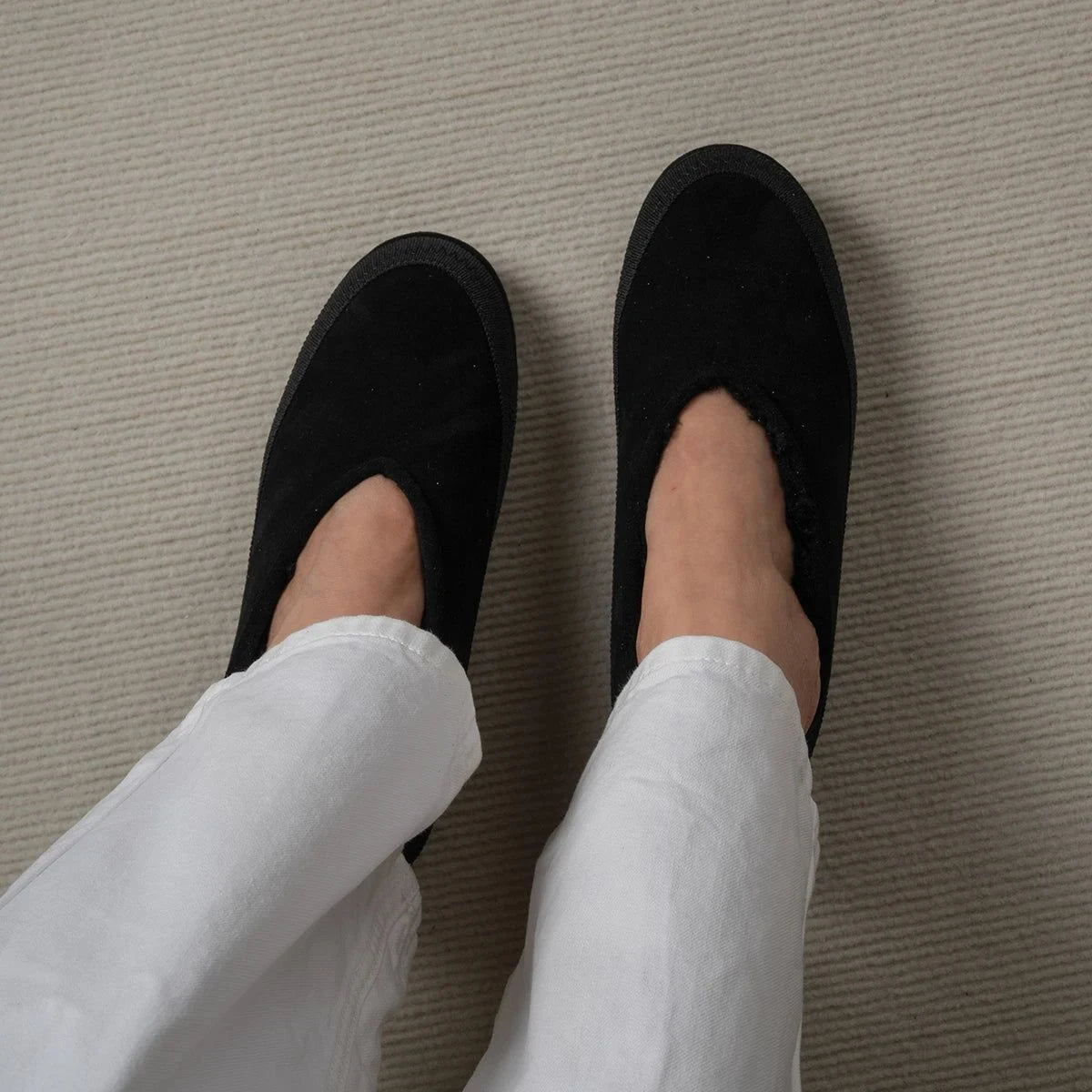 mocassins noirs vus d’au-dessus portés sur moquette claire