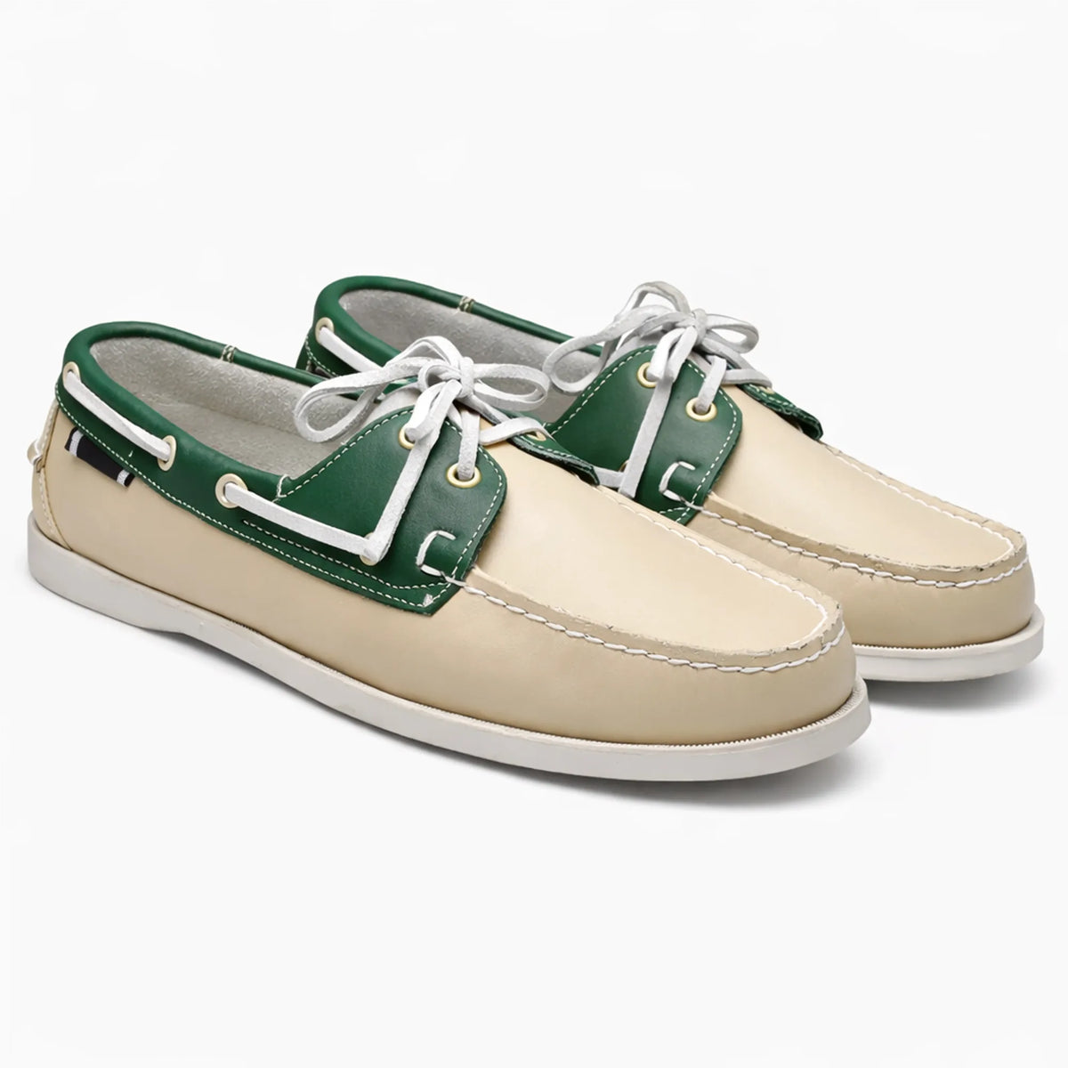 Paire de chaussures bateau beige et vert avec laçage blanc sur fond uni
