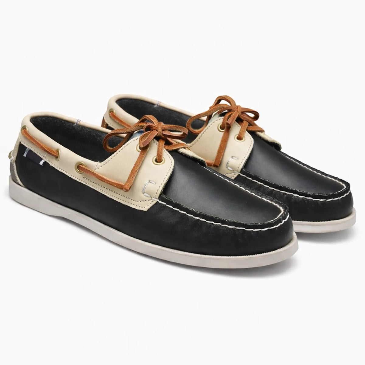 Paire de chaussures bateau noire et beige en cuir posée sur fond neutre