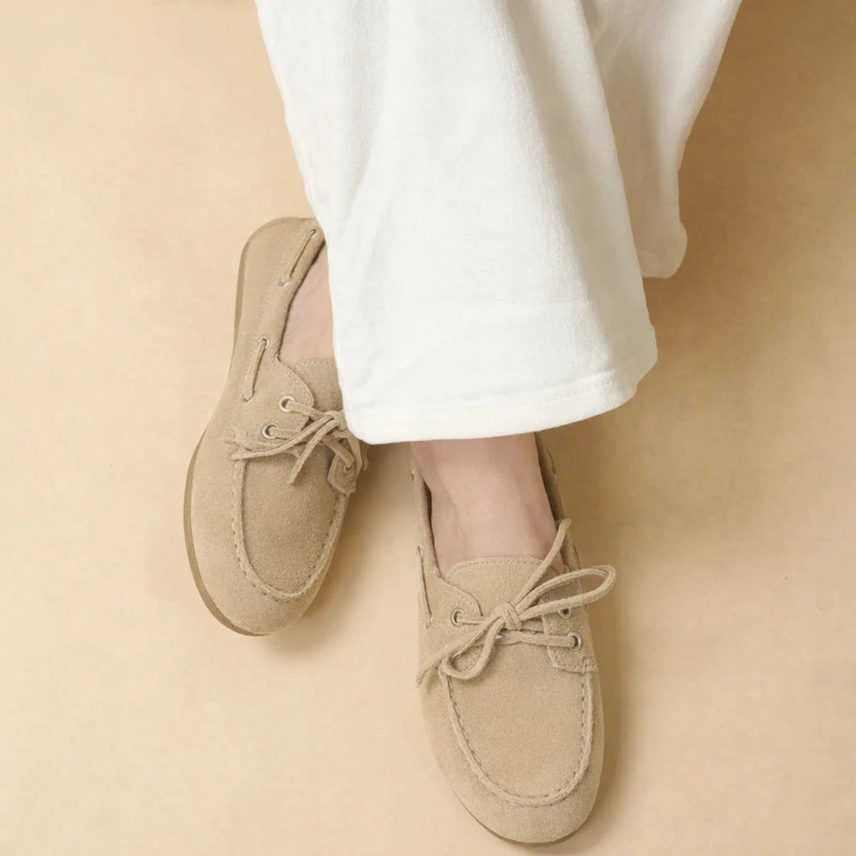 chaussures bateau beiges en daim portées avec un pantalon blanc