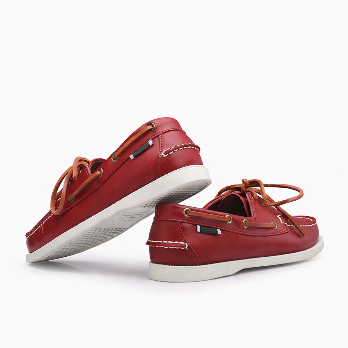 Paire de chaussures bateau rouge en cuir avec lacets beiges vue de biais