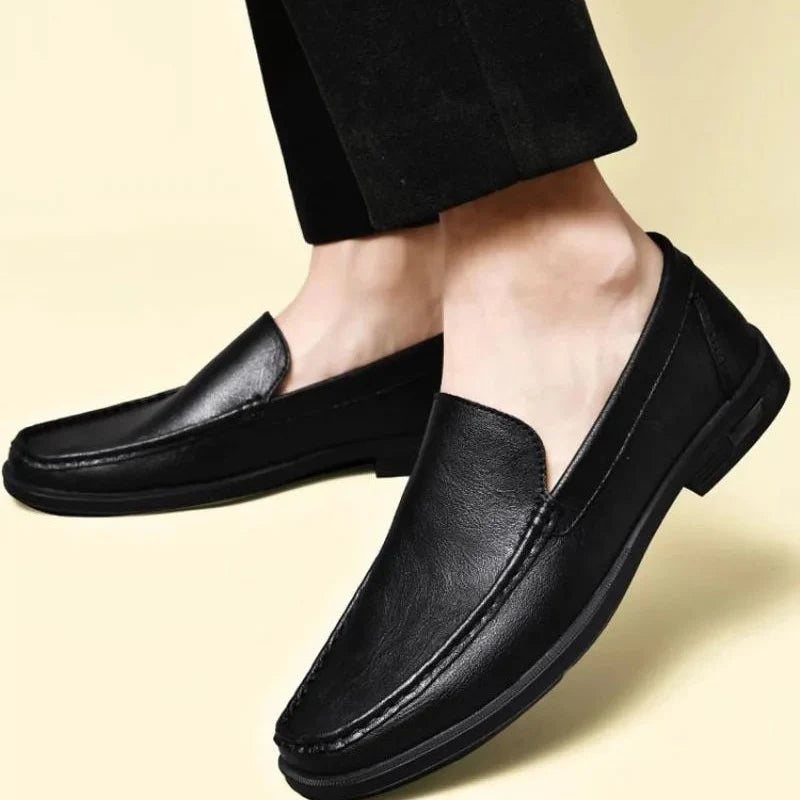 loafer noir porté vu de côté sur fond jaune pâle