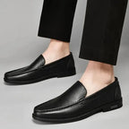 paire de loafers noirs portée avec un pantalon de costume noir