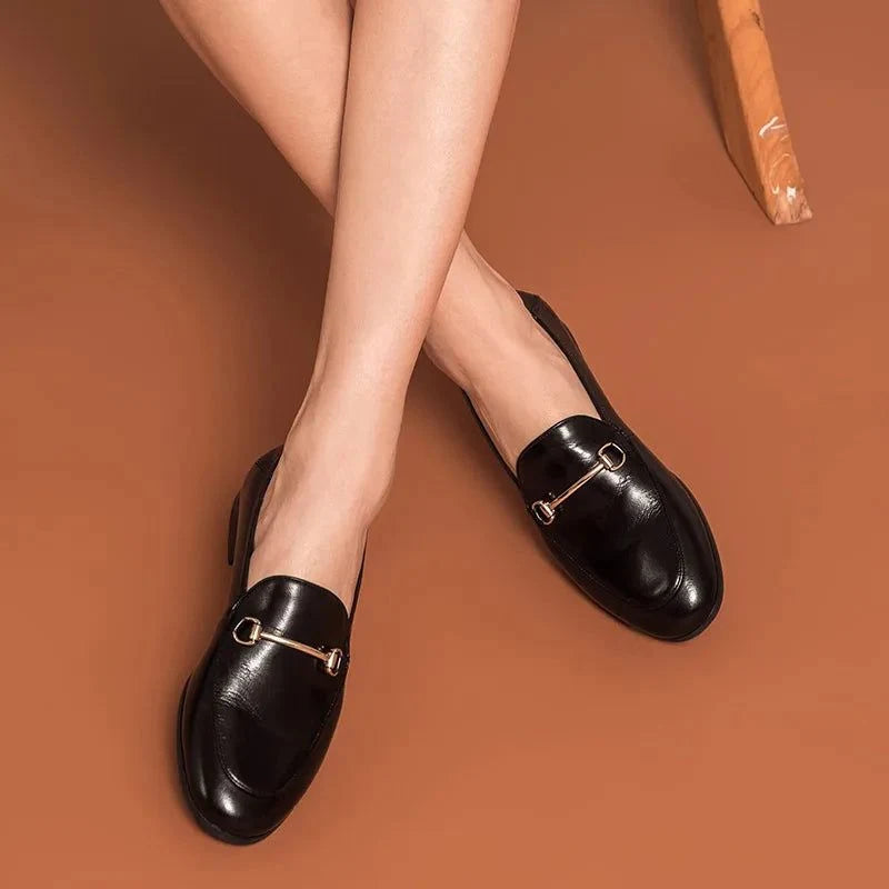 chaussures noires portées, jambes croisées sur sol marron