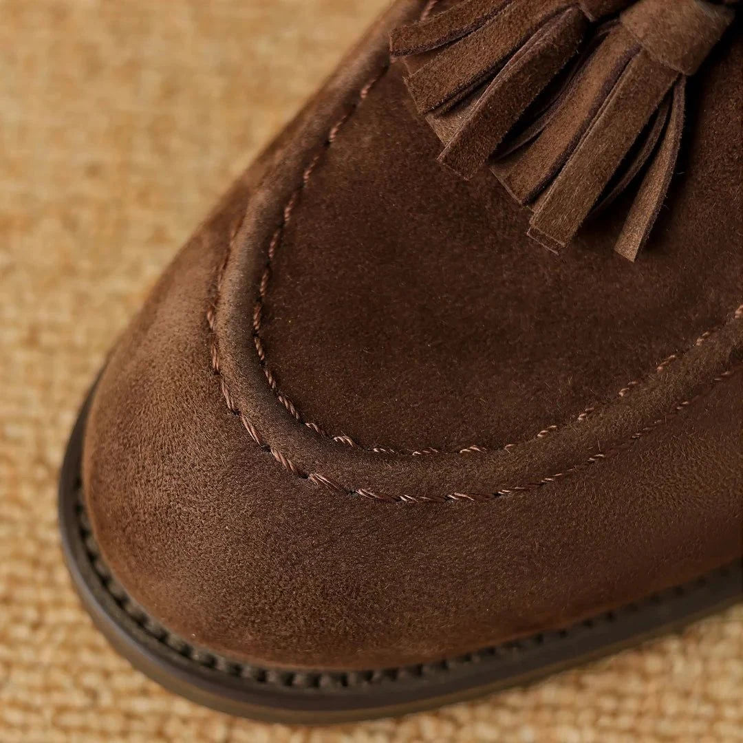 Gros plan sur les pompons et la couture du dessus du mocassin marron