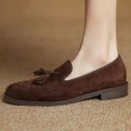 Mocassin marron vu de profil porté sur un tapis beige
