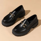 Paire de mocassins vernis noirs vue en trois-quarts sur fond uni beige
