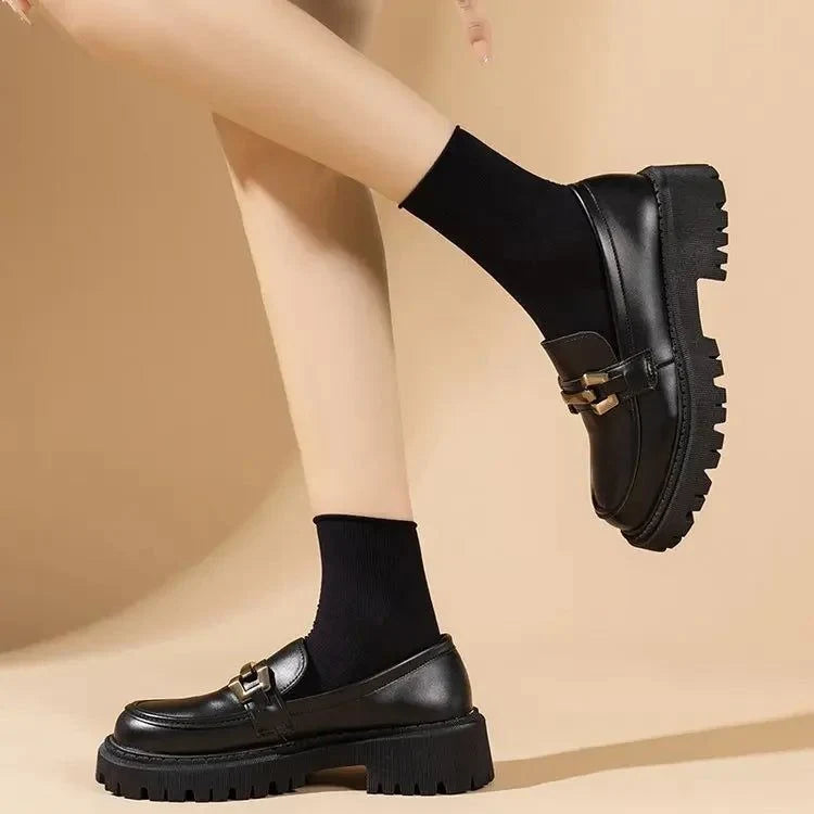 Mocassins noirs portés de profil avec des chaussettes noires, jambe croisée