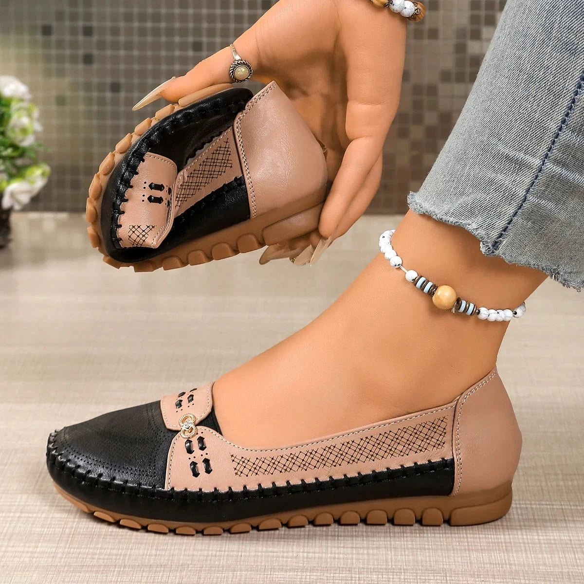 mocassin noir et rose tenu à la main, l'autre porté