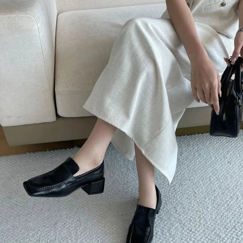 Mocassins noirs portés avec une jupe claire devant un canapé
