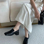 Mocassins noirs portés avec une jupe claire devant un canapé