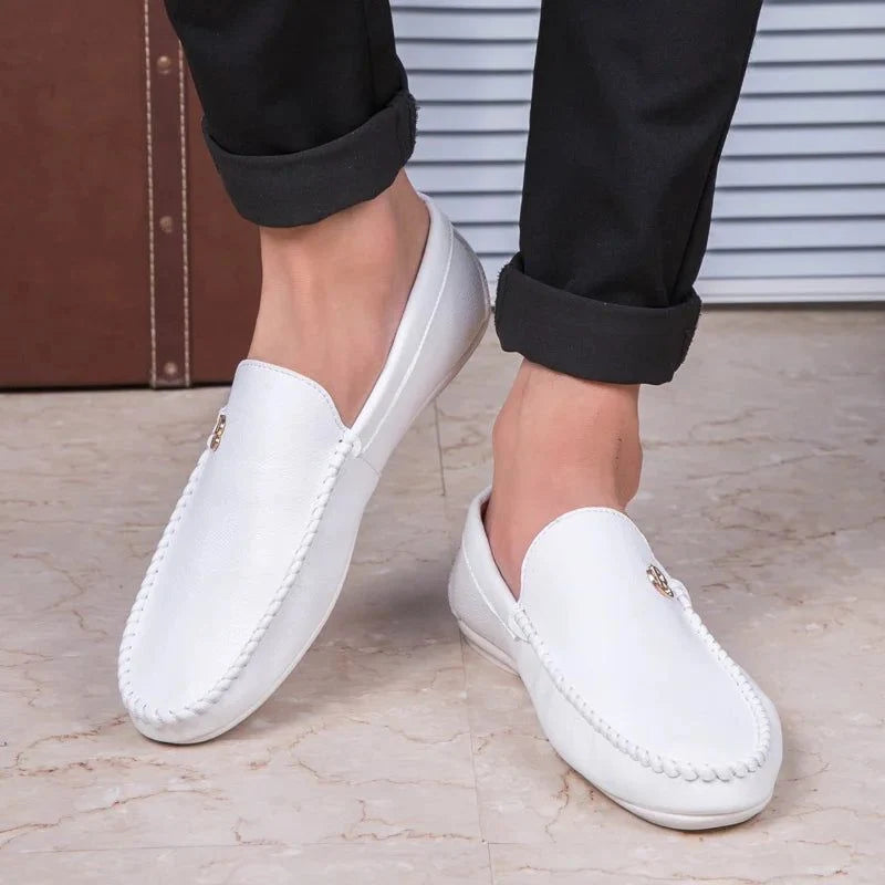 paire de mocassins blancs portée avec pantalon noir, pieds croisés
