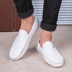 paire de mocassins blancs portée avec pantalon noir, pieds croisés
