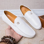 deux mocassins blancs portés par une personne debout en intérieur