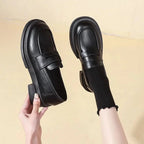 paire de mocassins noirs portée avec des chaussettes montantes noires