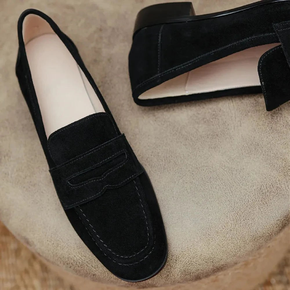 mocassin noir vu de dessus et de côté, posés sur tissu beige