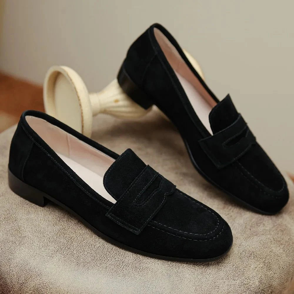 paire de mocassins noirs posée sur un fauteuil beige