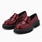 paire de mocassins vernis bordeaux posée sur fond uni clair