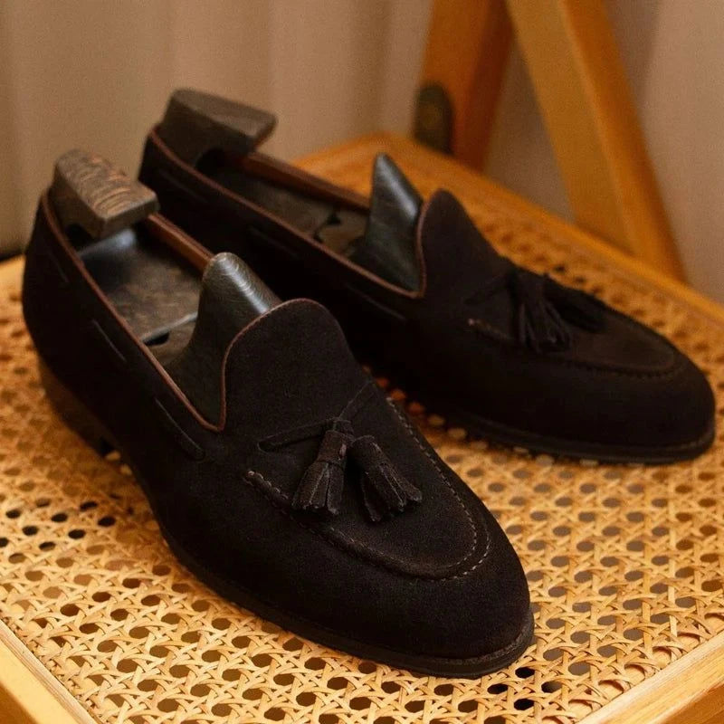 paire de mocassins foncés posée côte à côte sur une chaise à structure bois et cannage