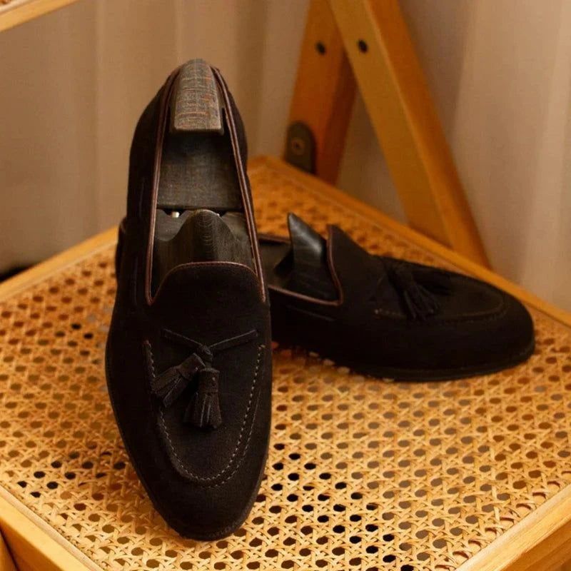 paire de mocassins en daim foncé posée sur une chaise en cannage dans un intérieur