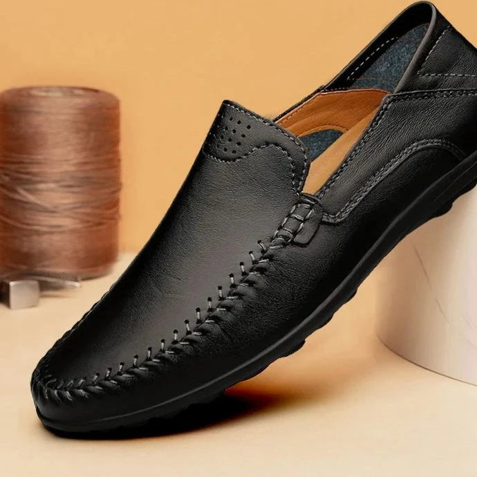 Mocassin noir posé devant un fil et un support cylindrique beige