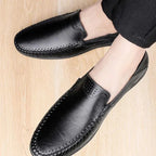 La paire de mocassins noirs vue portée sur un parquet clair