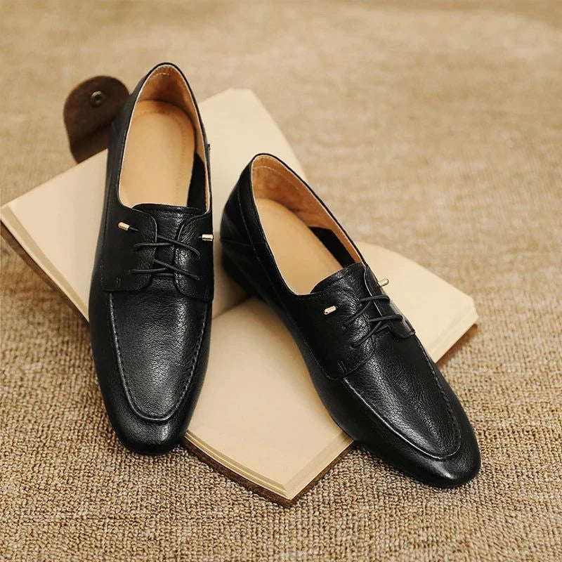 Paire de mocassins noirs vue de dessus, posée sur deux livres