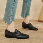 Deux mocassins noirs portés, le modèle debout sur tapis beige
