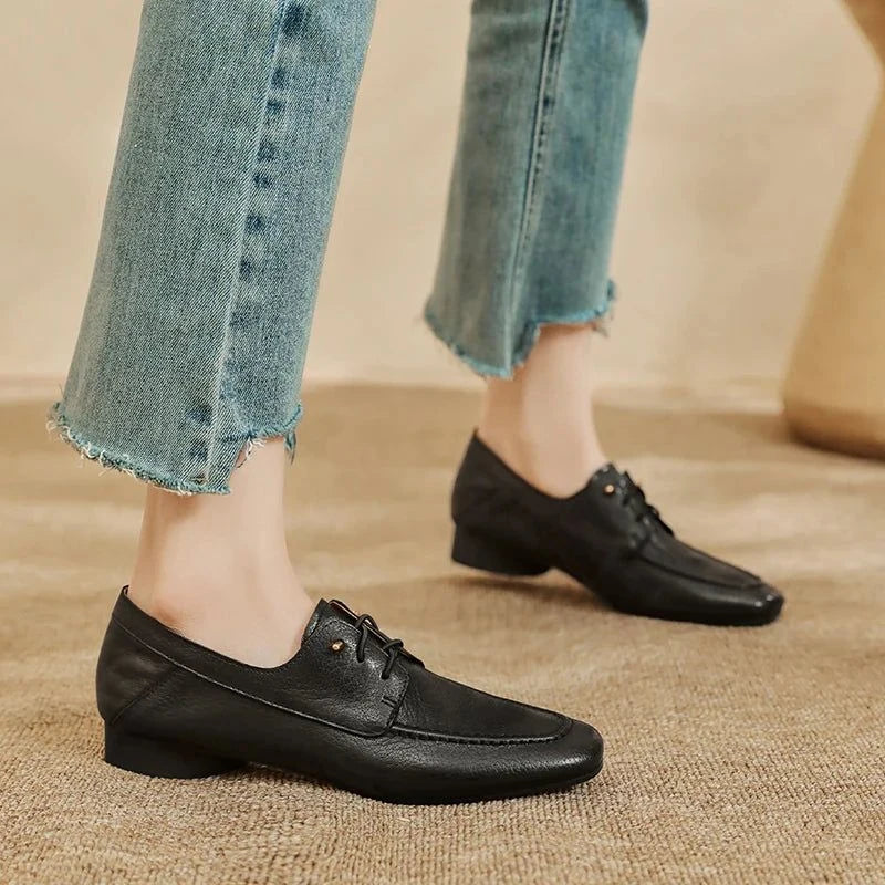 Deux mocassins noirs portés, le modèle debout sur tapis beige