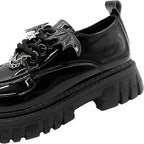 gros plan d’un mocassin derby vernis noir vu de côté, semelle crantée et ailes de chauve-souris