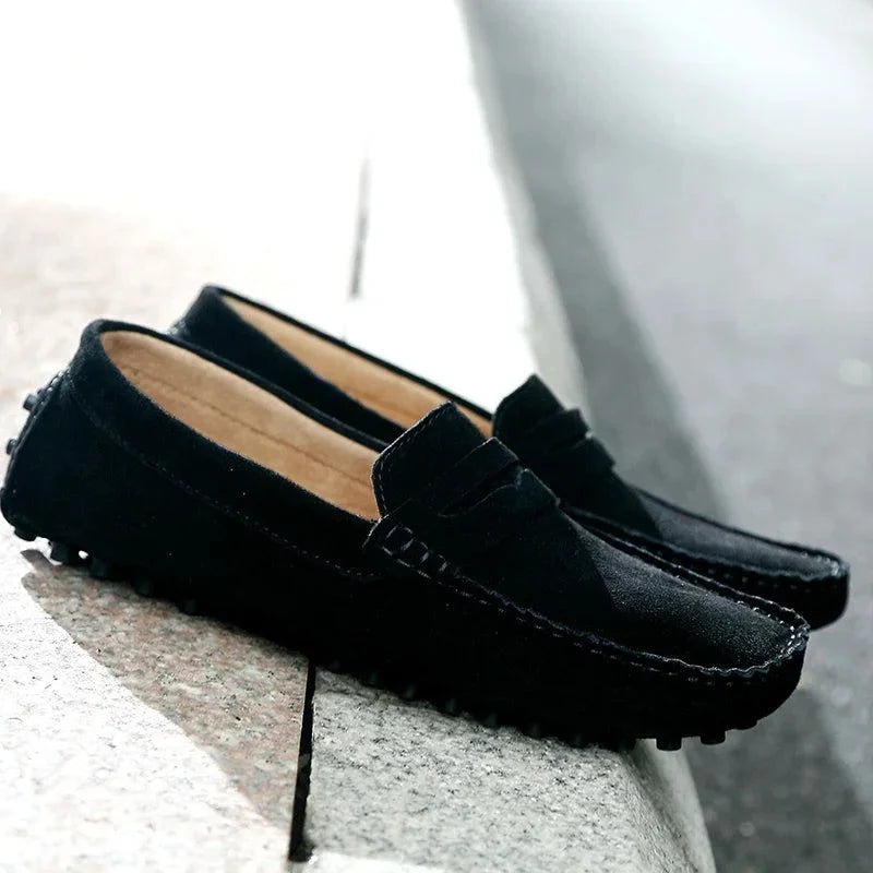 Paire de mocassins noirs posée près d’un trottoir, vue en perspective