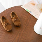 paire de mocassins marron vue de dessus sur une table en bois