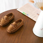 deux mocassins marron posés sur une table avec journal en arrière-plan