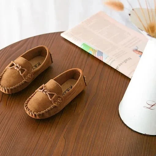 deux mocassins marron posés sur une table avec journal en arrière-plan