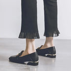 Talon et arrière du mocassin noir portés, pantalon noir à ourlet plissé visible