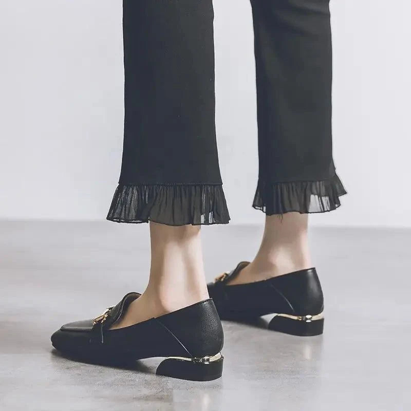 Talon et arrière du mocassin noir portés, pantalon noir à ourlet plissé visible