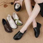 Trois paires de mocassins posées au sol, une paire noire portée