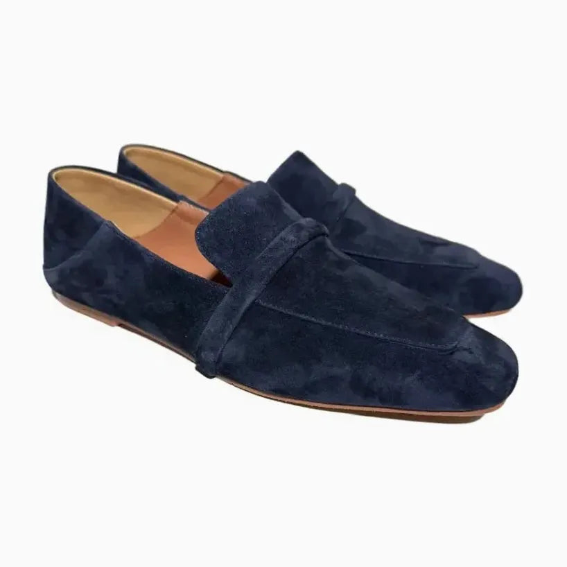 Mocassins en daim bleu marine tournés légèrement de côté sur fond uni