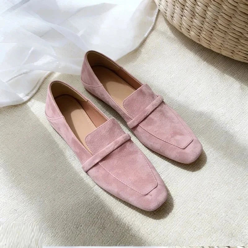 Paire de mocassins en daim rose placée à côté d’un tapis clair