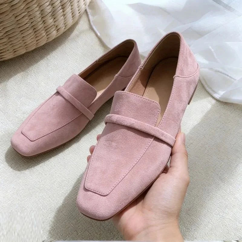 Mocassin rose en daim tenu en main, le second posé à côté