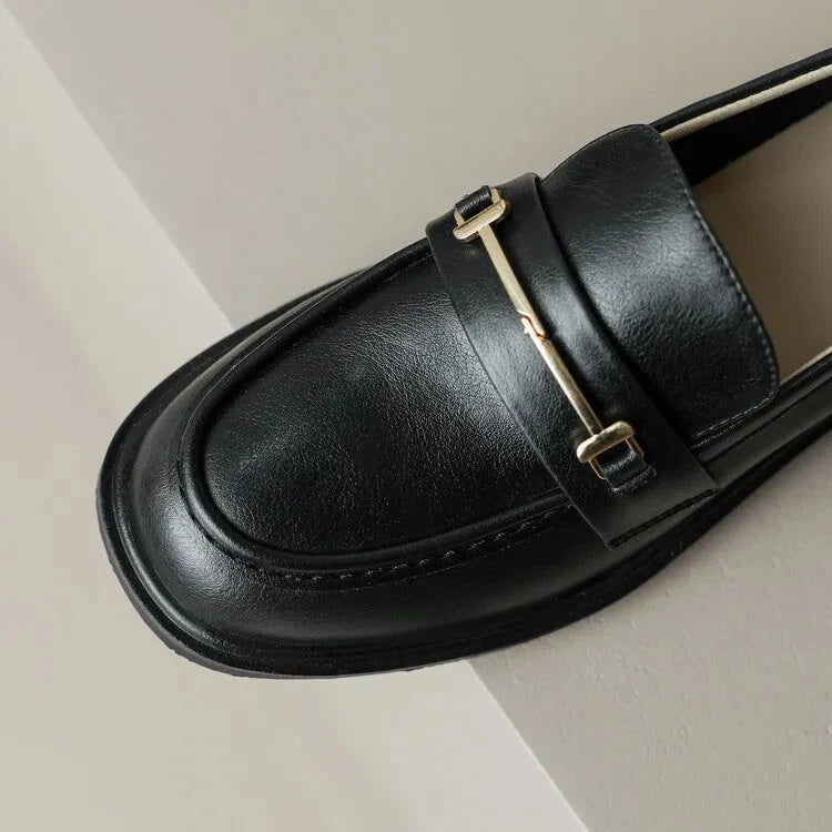 gros plan sur la chaîne métallique dorée d’un mocassin noir en cuir