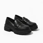 Mocassin femme semelle épaisse noir posé sur fond uni clair