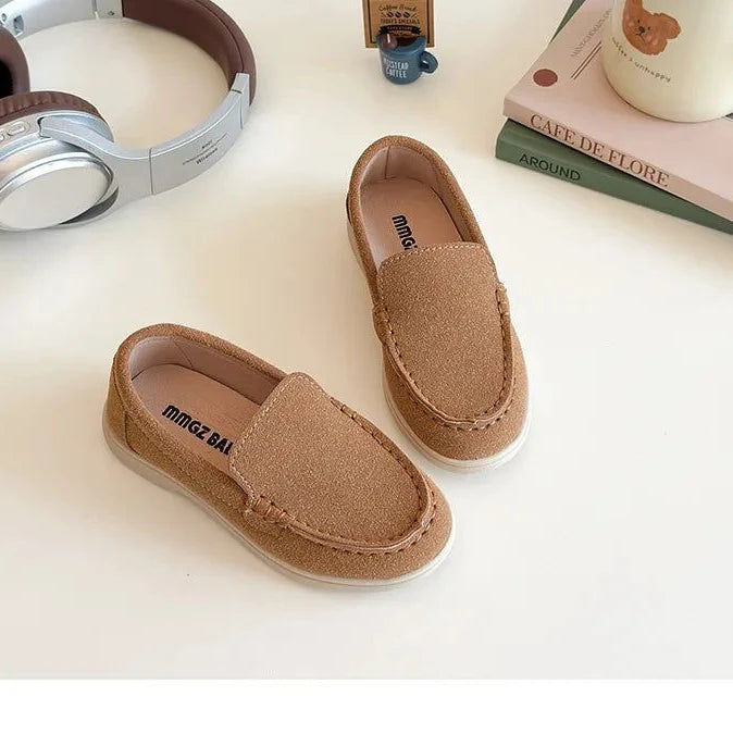 paire de mocassins marron sur un bureau près de livres et tasse à ours